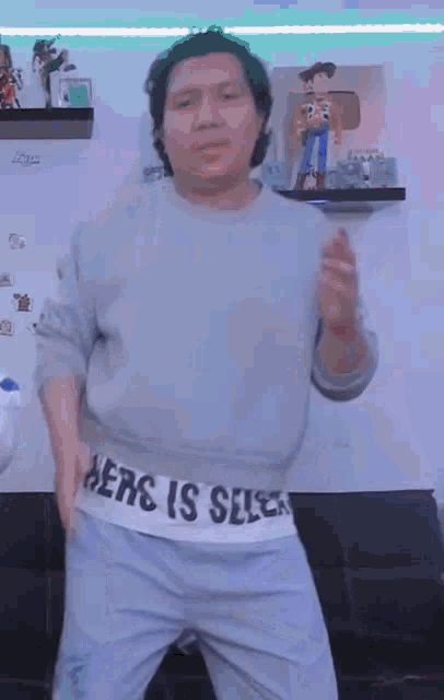 a man wearing a sweater that says `` here is selca '' is dancing .