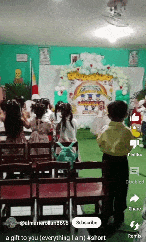 a group of children are standing in front of a stage with a sign that says ' a gift to you ' on it