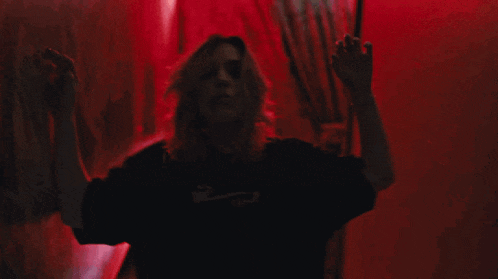 a woman in a black shirt is dancing in front of a red background