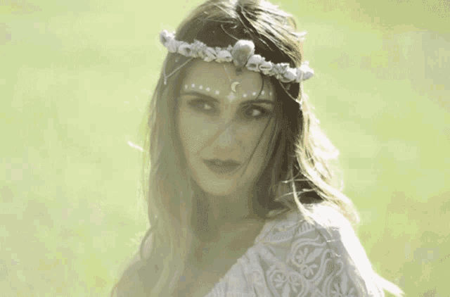 a woman wearing a flower crown on her head looks at the camera