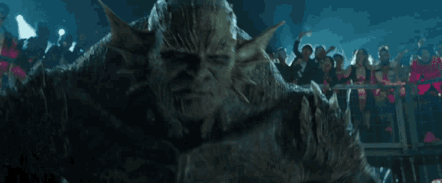a close up of a monster 's face with a crowd behind him
