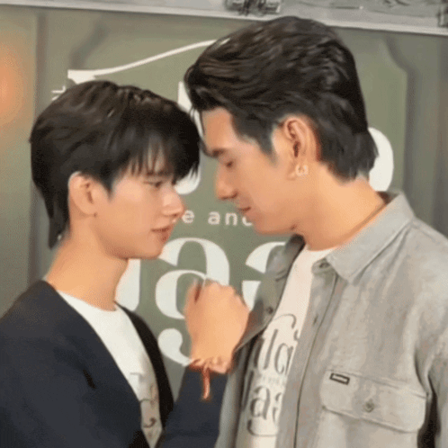 two men are touching their noses in front of a sign that says e and a