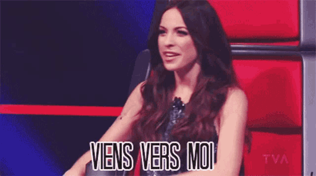 a woman sitting in a red chair with the words " viens vers moi " written on it