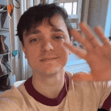 a young man is waving his hand in front of a shoe shelf