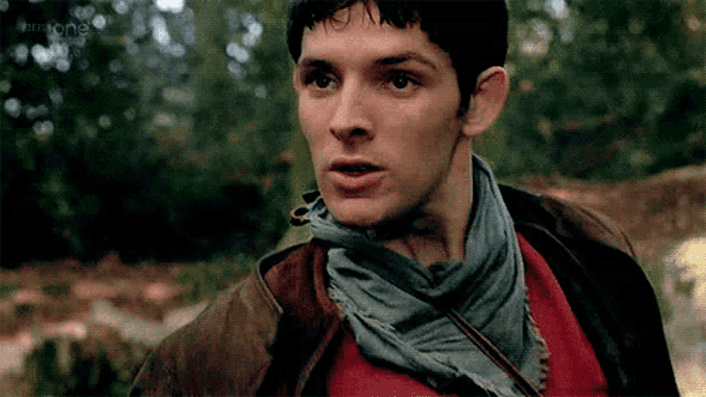 a close up of a man wearing a scarf around his neck and a brown jacket .