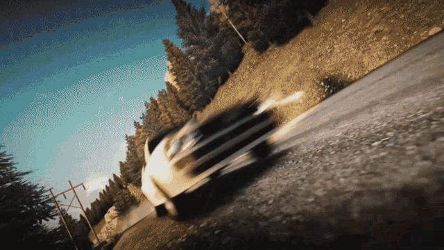 a white car is driving down a dirt road with trees in the background