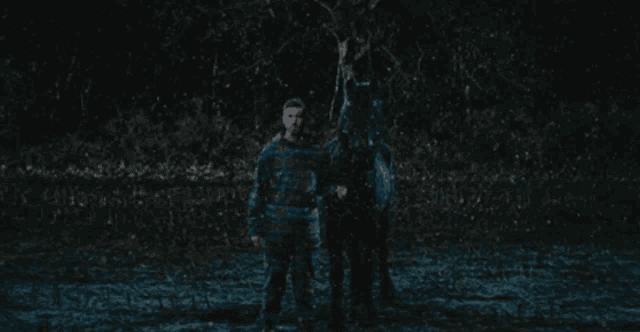 a man in pajamas stands next to a horse in a muddy field