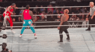 two men are wrestling in a wrestling ring with a referee watching .