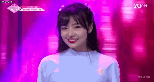 a girl in a blue shirt is smiling on a stage .