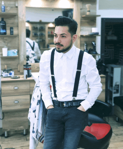 a man wearing suspenders and a white shirt stands in a barber shop