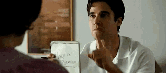 a man is talking to a woman while holding a piece of paper that says `` they 're going '' .
