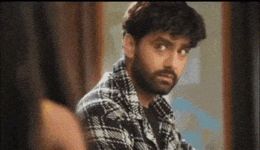 a man with a beard is looking at himself in the mirror and making a funny face .