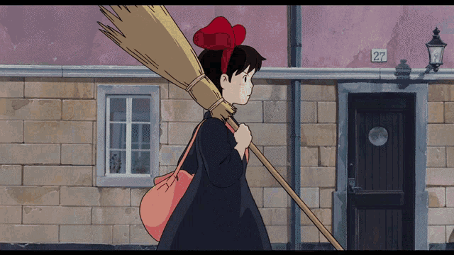 a girl carrying a broom in front of a building with the number 27