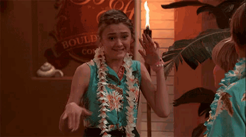 a girl wearing a lei is standing in front of a sign that says boulder co.