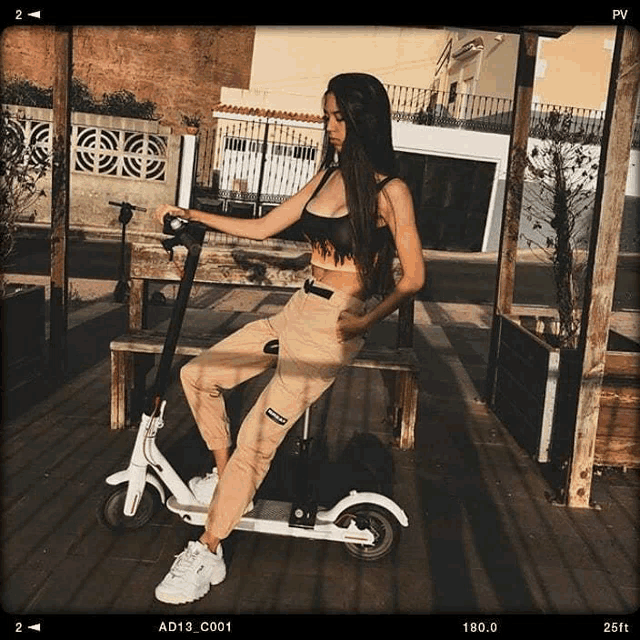 a woman sits on a bench holding a scooter with ad13 c001 written on the bottom