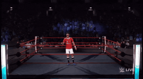 a man in a red shirt and white shorts is walking into a wrestling ring
