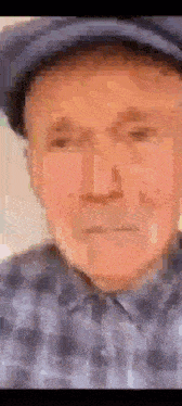 a pixelated image of an older man wearing a hat and a plaid shirt .