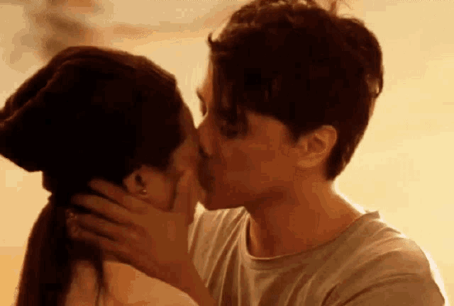 a man and a woman are kissing in front of a sunset .
