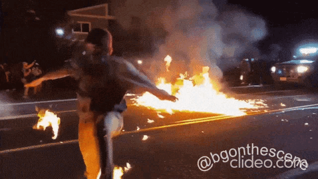 a man stands in front of a burning car with a watermark that says @bgonthesescene