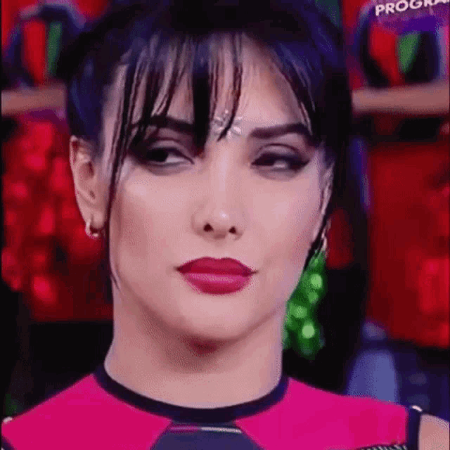 a close up of a woman 's face with red lipstick and black hair making a funny face .