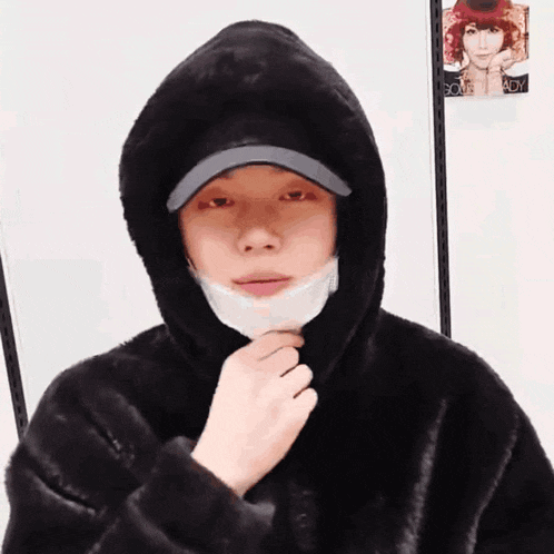 a person wearing a hooded jacket and a mask on their face .