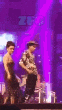 a man and a woman are dancing on a stage in front of a purple background that says zfc