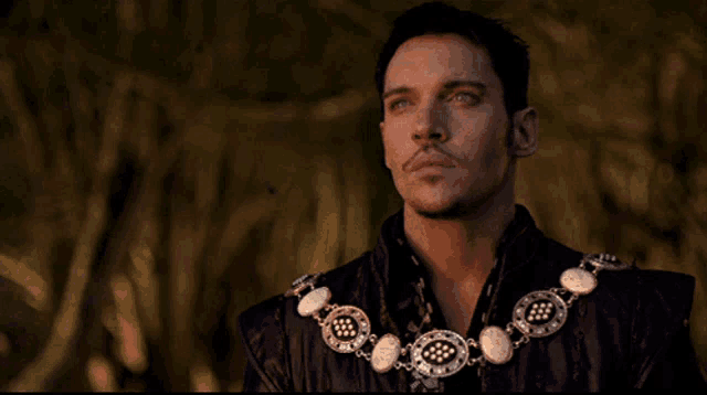 a man with a necklace around his neck is looking up