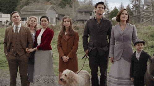 a group of people standing in a field with a dog