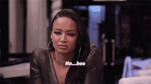 a woman in a black dress is sitting at a table with her eyes closed and says no ... boo .
