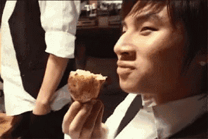 a man in a white shirt is holding a piece of food in his hand