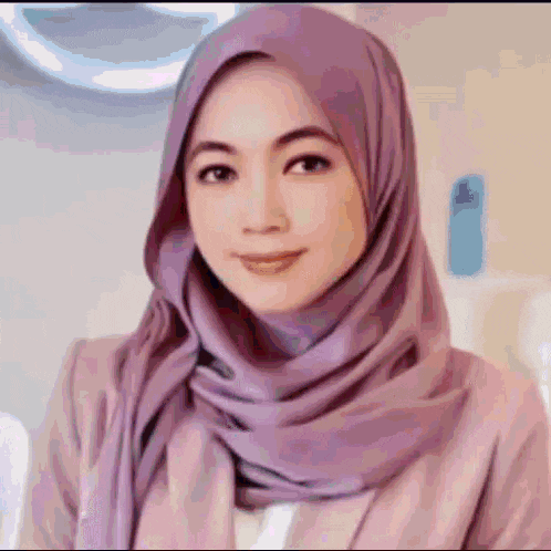 a woman wearing a purple hijab and a pink jacket is looking at the camera .