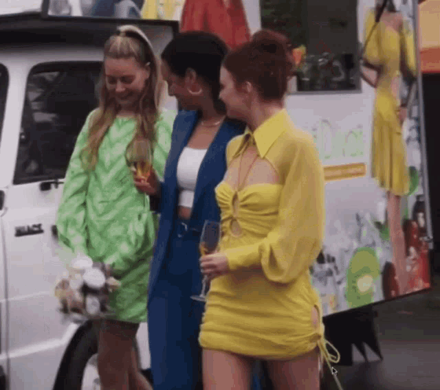 three women are standing in front of a white van that says duoli on the side