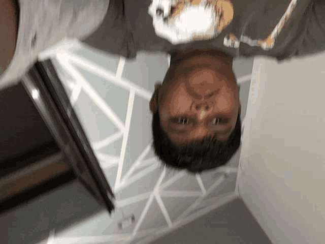 a man 's head is upside down and he is wearing a t-shirt with a picture of a penguin on it