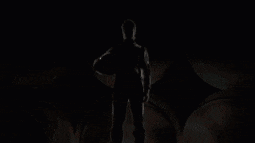 a silhouette of a man standing in front of a bright red light