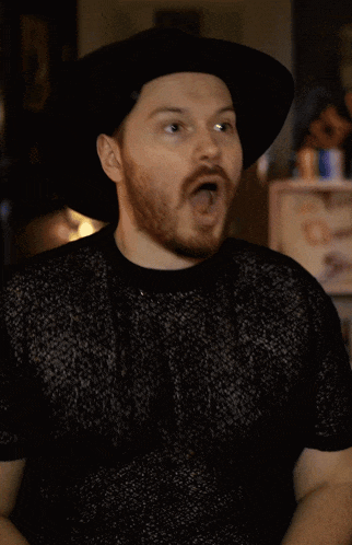 a man with a beard wearing a hat and a black shirt