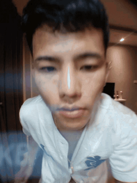 a close up of a man 's face with a white shirt that says u on it