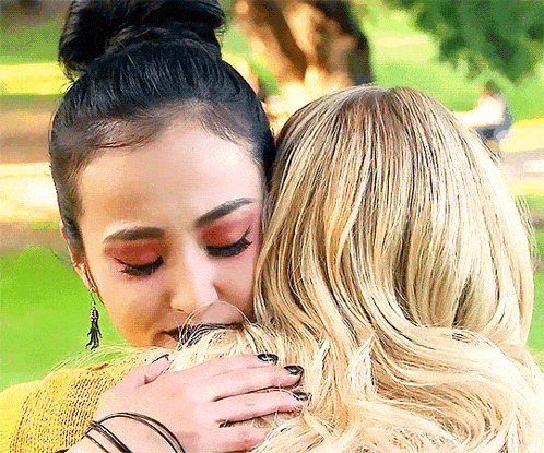 a woman hugging another woman in a park