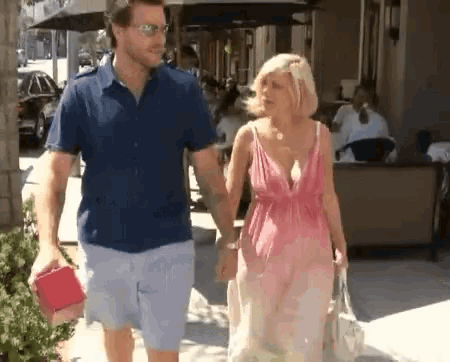 a man and a woman are walking down the sidewalk holding hands