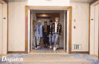 a group of people walking out of an elevator with an exit sign