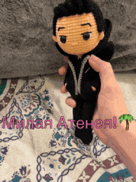 a person is holding a crocheted doll in their hand with a palm tree in the corner