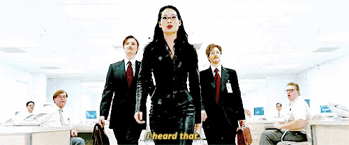 a woman in a black suit says " i heard that " in front of a group of people