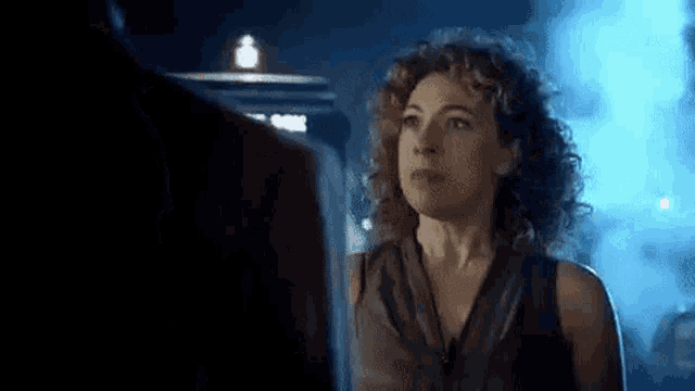a woman is standing next to a man in a dark room in front of a police box .