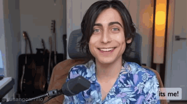 a young man is smiling in front of a microphone with the words " its me " below him
