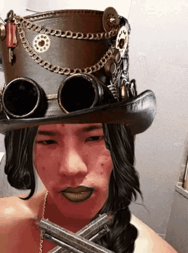 a person wearing a top hat and goggles has a cross in front of their face