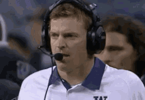 a football coach wearing headphones and a tat shirt