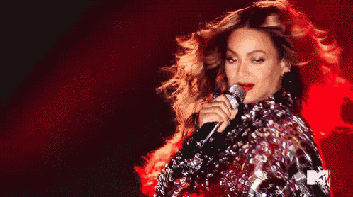 a woman singing into a microphone with a red background