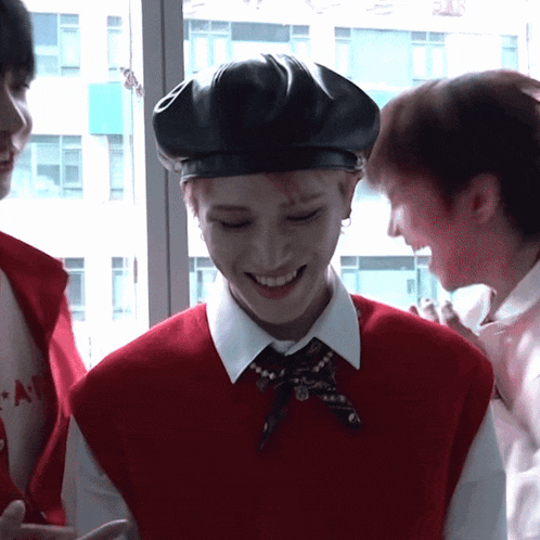 a man wearing a red vest and a black beret smiles