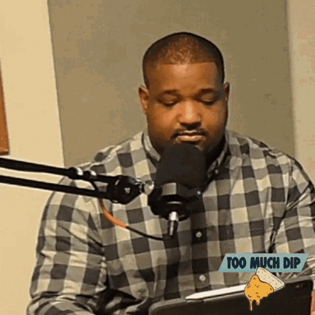 a man in a plaid shirt is sitting in front of a microphone with the words too much dip below him
