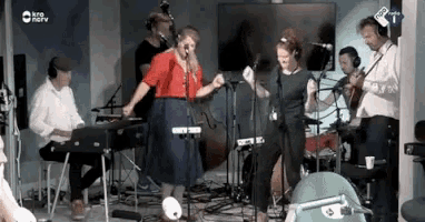a group of people are singing and playing instruments in front of a tv screen that says ' npo ' on it