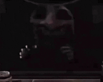 a close up of a person 's face with horns and a skull in a dark room .